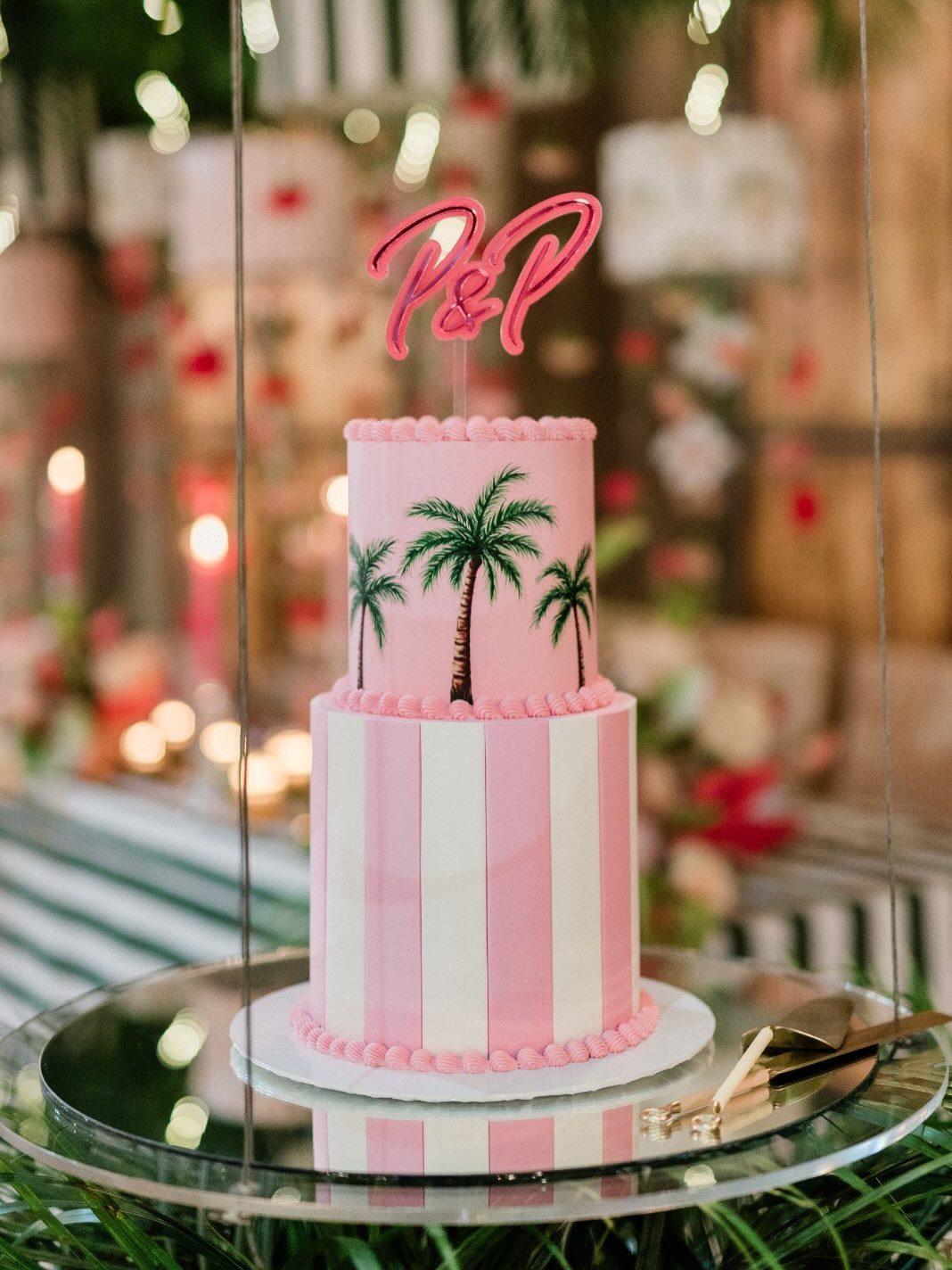 Wedding cake with tropical palm-leaf decoration and a couple's monogram topper