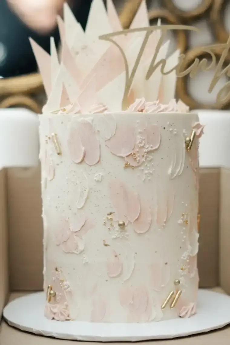 Blush pink textured cake with a white chocolate shard crown and gold accents, “Thirty” script topper