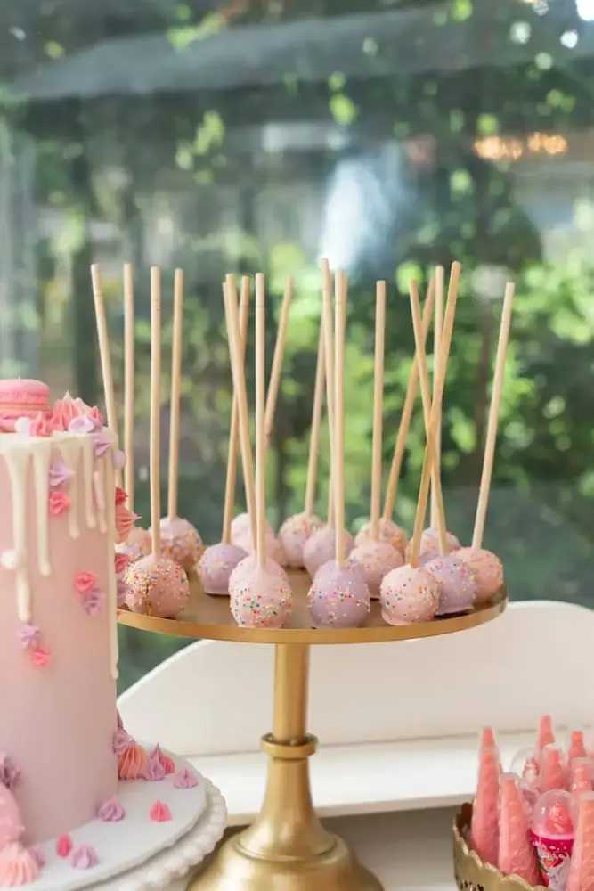 Sprinkle-coated cake pops on sticks from a pink-themed dessert table