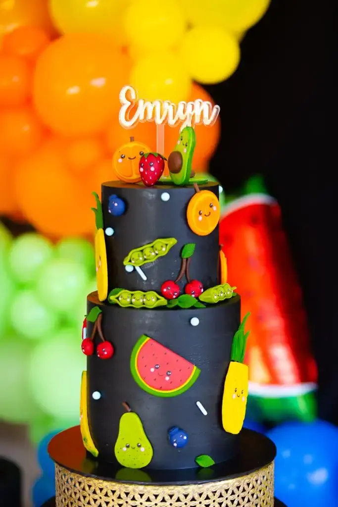 Black two-tier cake decorated with cute cartoon-style fruit characters